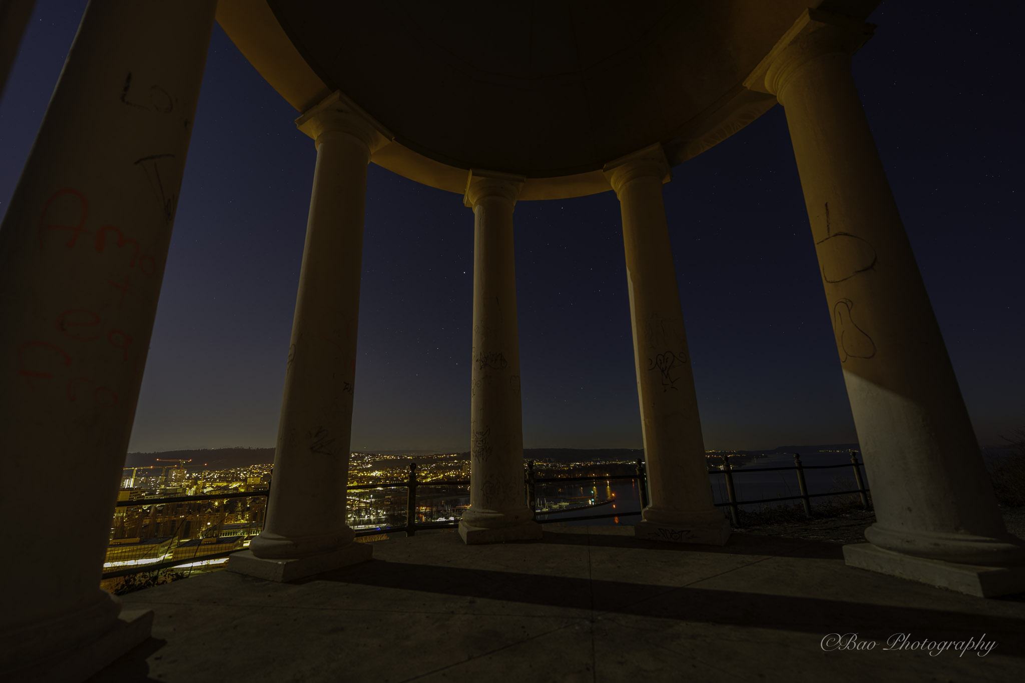 Night view through Pavillon Felseneck with stone columns overlooking Biel and the lake