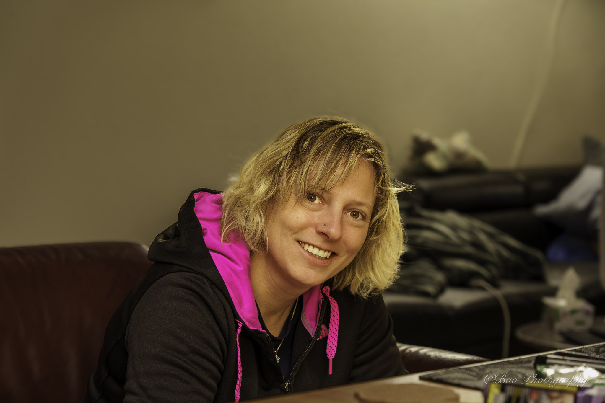 Casual indoor portrait of Sara smiling with blonde hair in warm ambient light