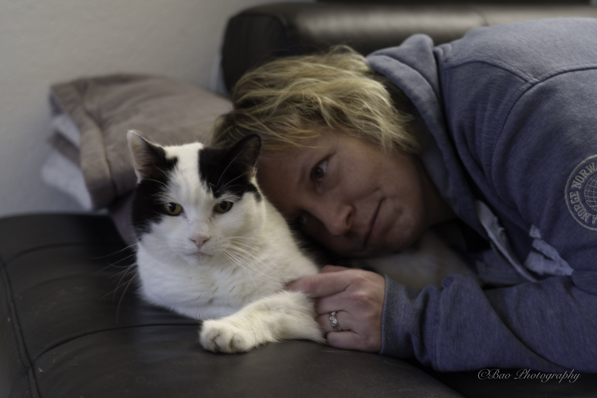 Sara resting on a couch beside her cat Dionysos, both looking at the camera